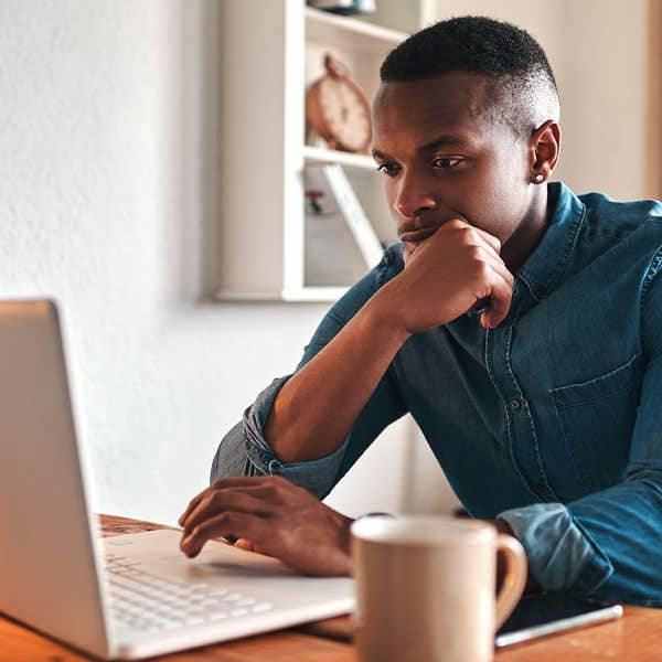 Journalist reading on a laptop at a desk with a mug of coffee