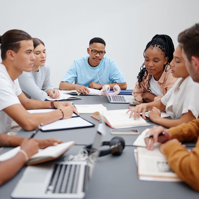 Students working together around a table with laptops and notebooks