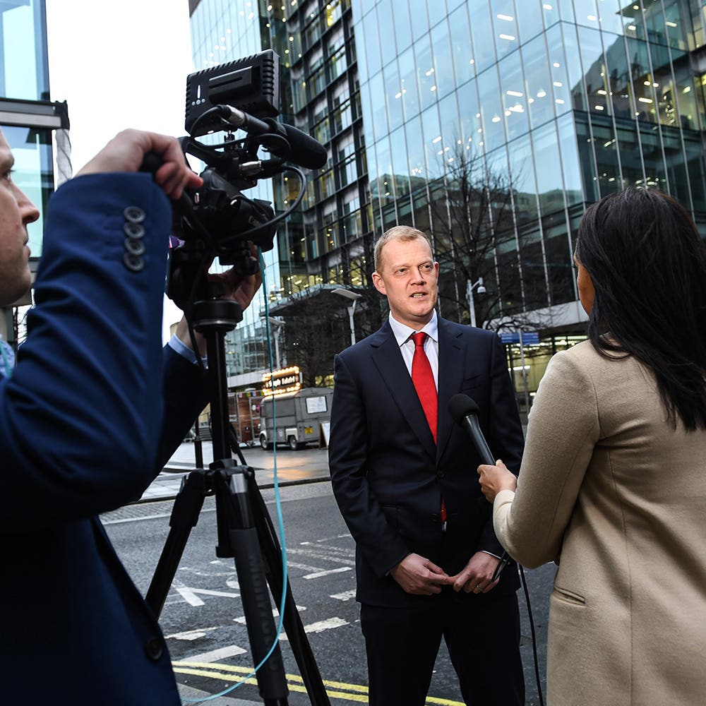 Spokesperson being interviewed by a television news crew outside an office building