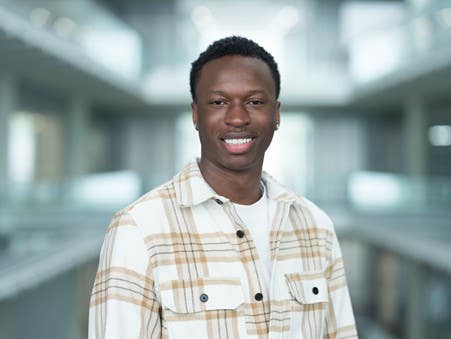 Portrait of a smiling journalism graduate in a checked shirt