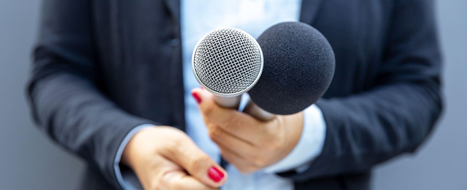 Interviewer holding two microphones towards a contributor