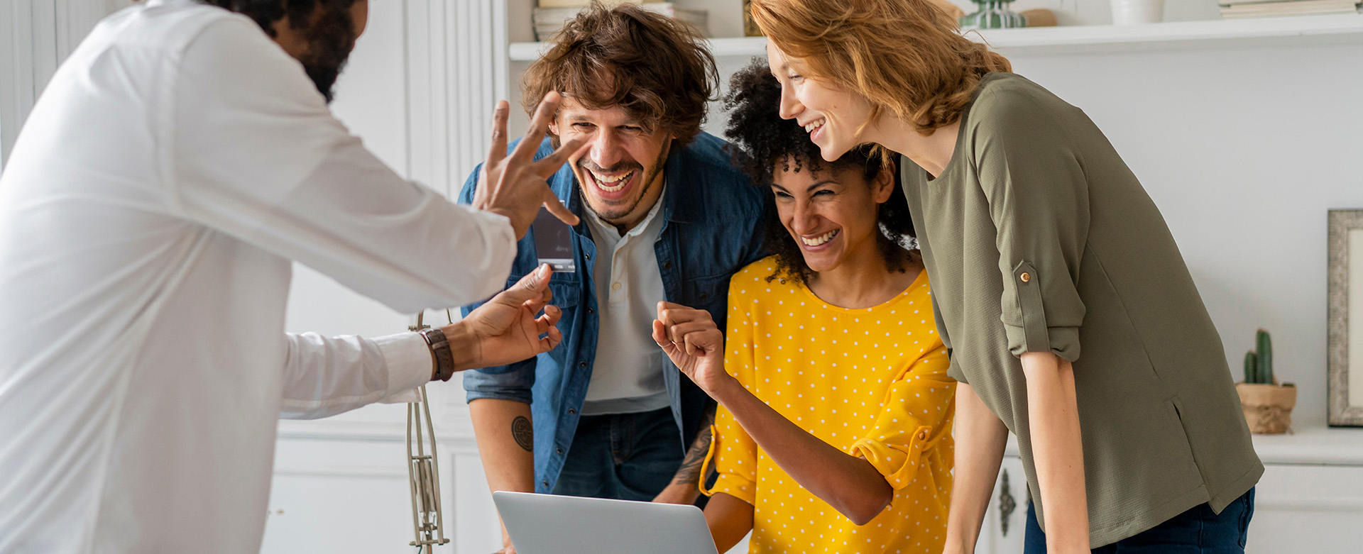 Group of colleagues celebrating together around a laptop