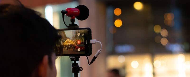 Content creator filming on a phone with a clip-on microphone at night