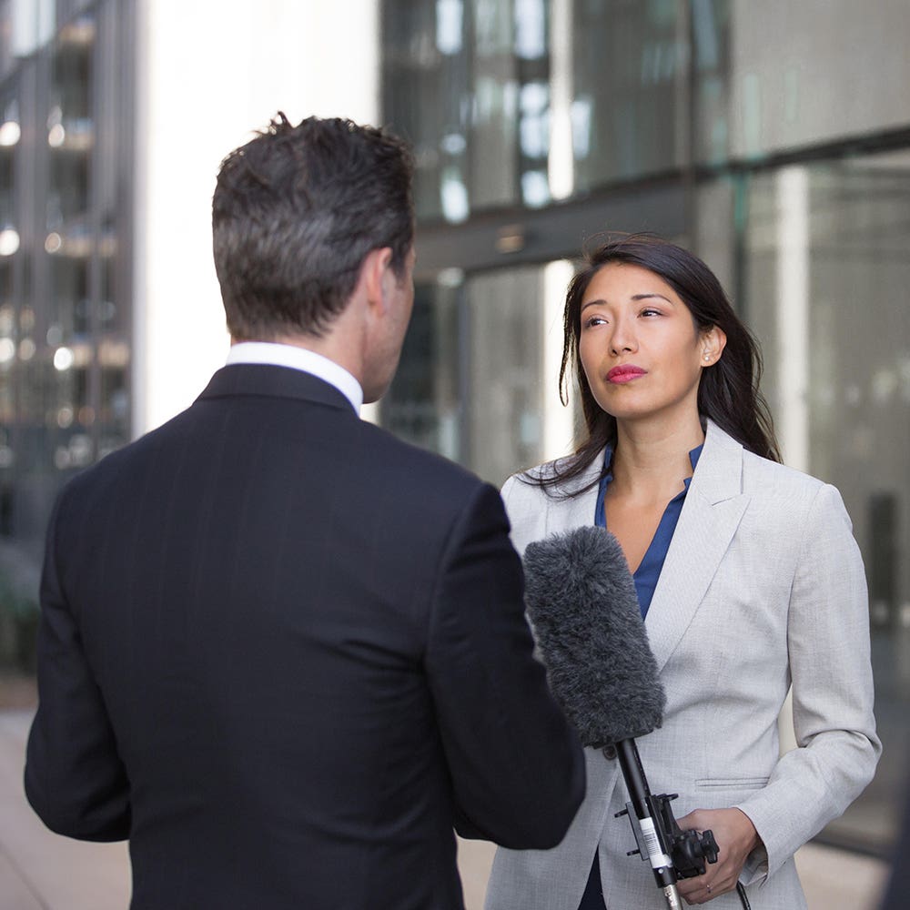 Spokesperson answering questions from a reporter holding a boom microphone