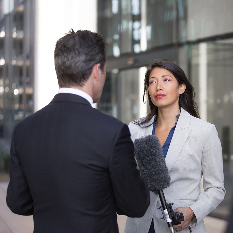 Spokesperson answering questions from a reporter holding a boom microphone