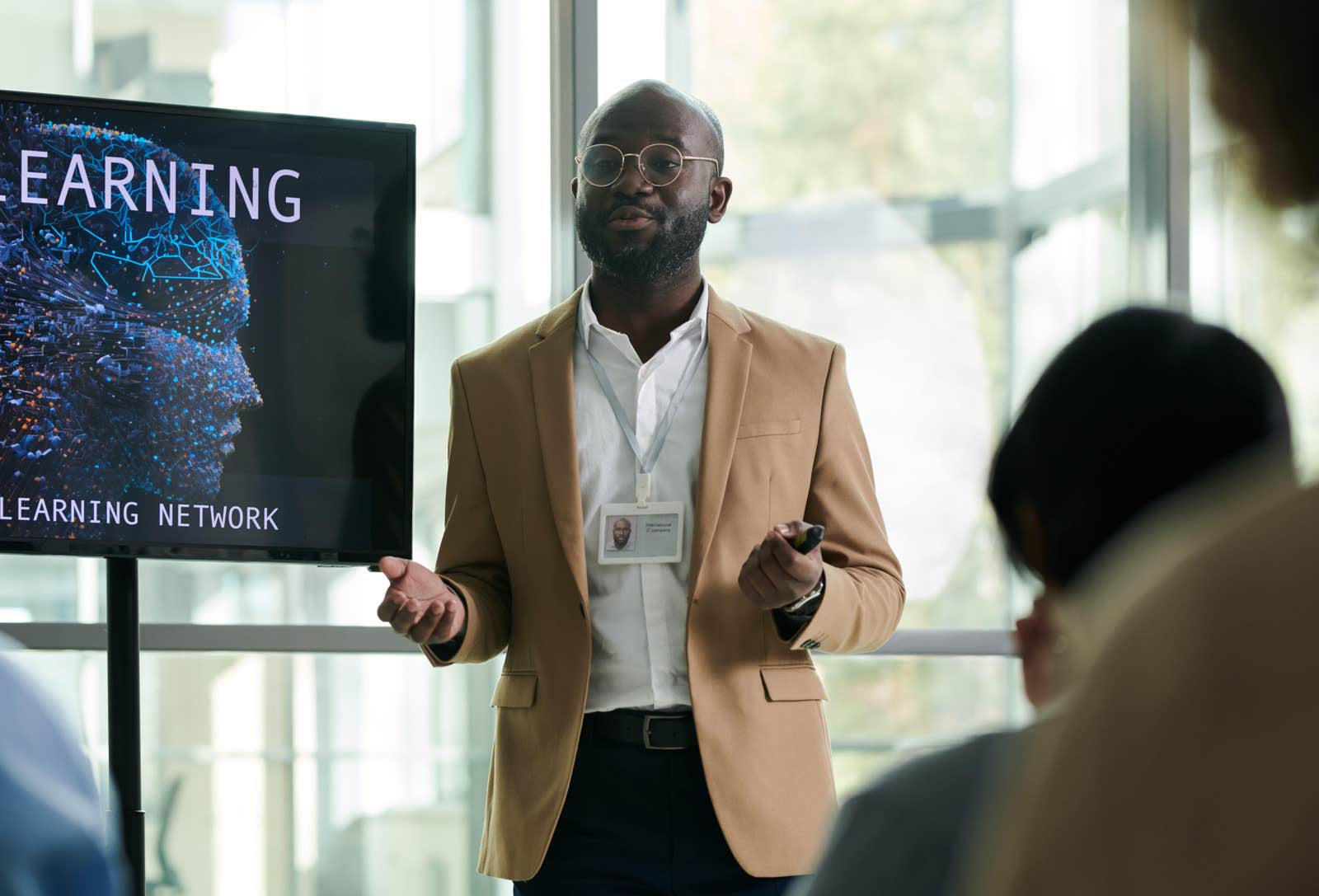 Young man in formalwear standing by interactive board while explaining points of his presentation to audience during conference
