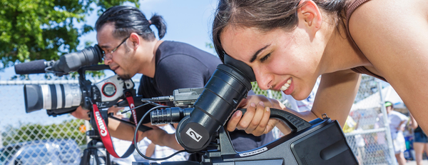 Two Journalism Summer School students operating professional video cameras outdoors
