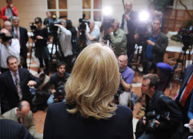 Speaker facing a press pack of photographers and camera crews at a news conference