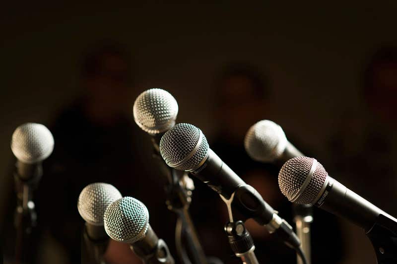 A group of microphones set up for a news conference