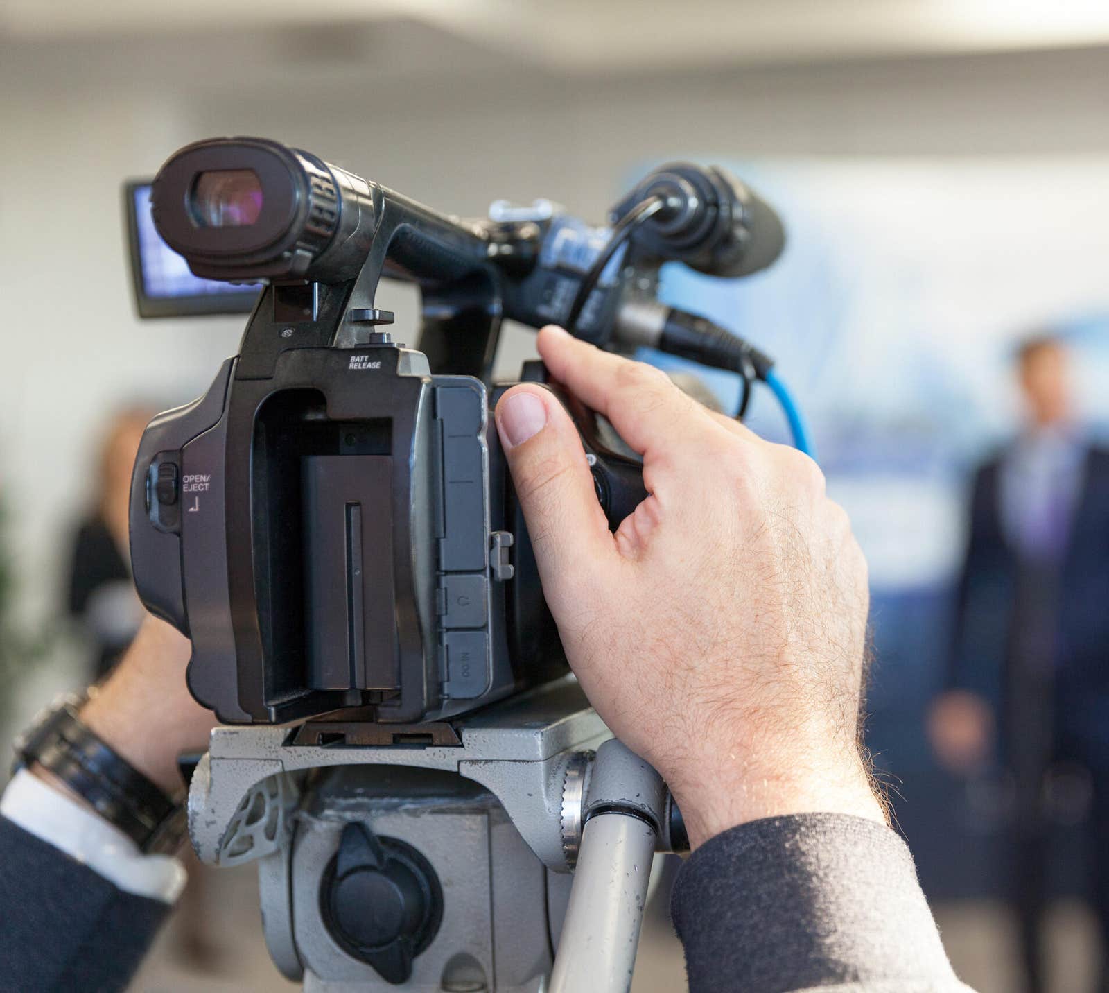 Camera operator filming a spokesperson at a press conference