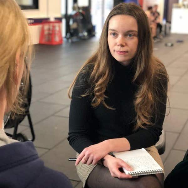 Trainee journalist interviewing a contact and taking shorthand notes at an event