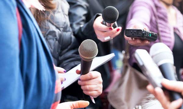 Reporters holding microphones and voice recorders towards a spokesperson