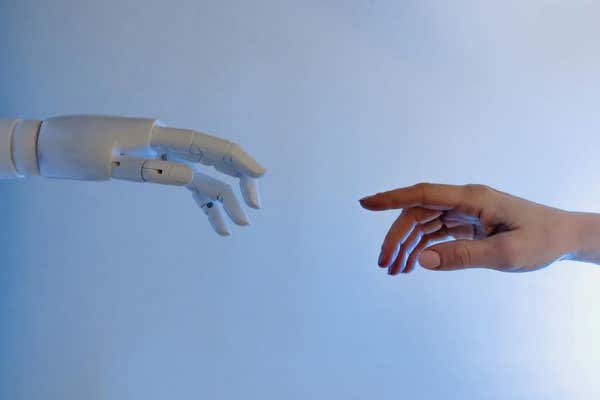 A robotic hand and a human hand reaching towards one another