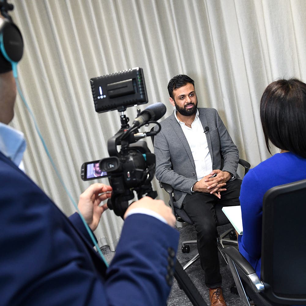 Spokesperson filmed by a camera crew during a seated studio interview