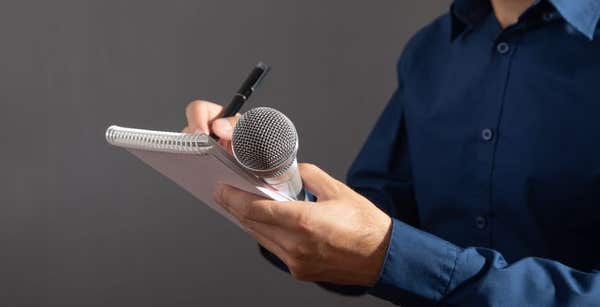 caucasian-journalist-holding-microphone-notepad-pen.jpg