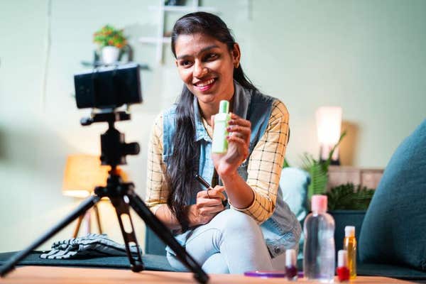 2GN7D75 young Indian girl reviews make up cosmetic product to fans on her channel by recording video, concept of online influ