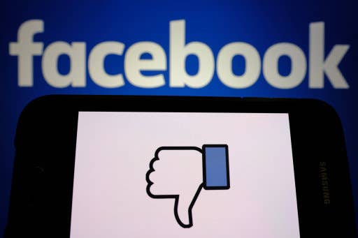 An upside-down thumb is displayed in front of a Facebook logo in Portland, Ore., on March 21, 2018. Cambridge Analytica repor