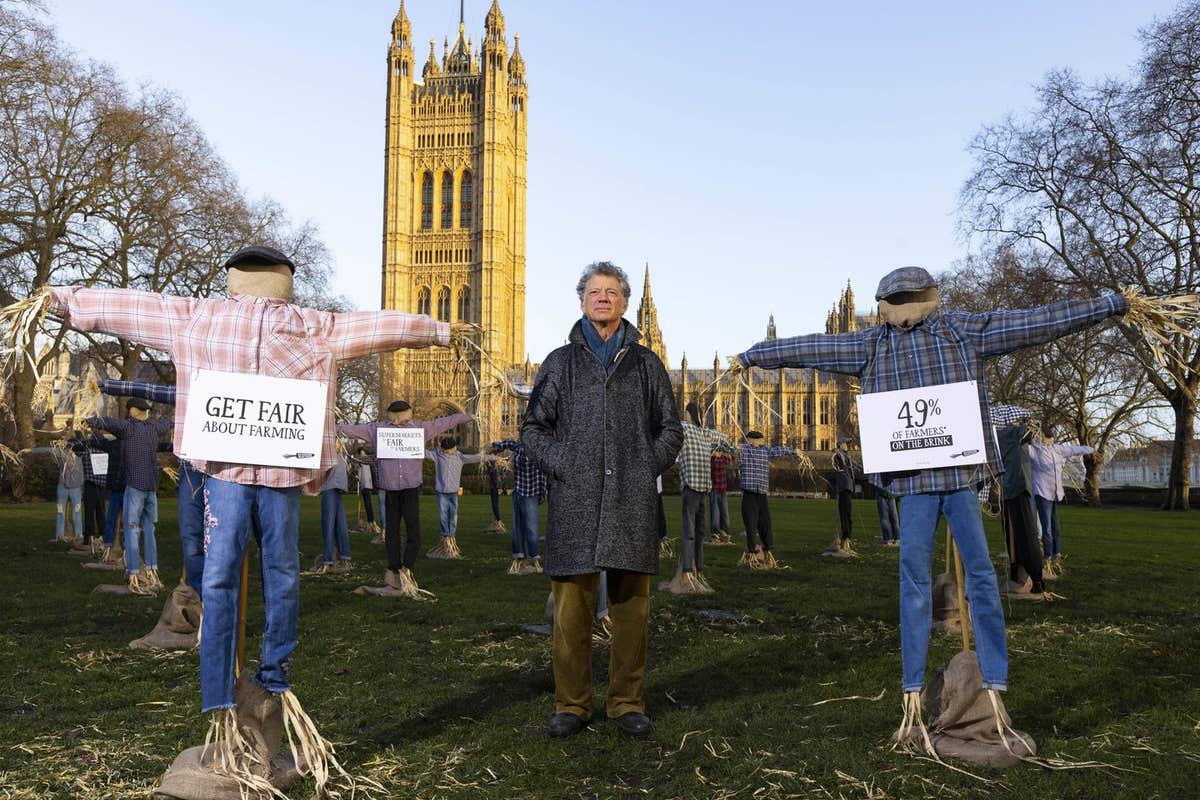 EDITORIAL USE ONLY Riverford founder Guy Singh-Watson in front of 49 scarecrows outside the Houses of Parliament in London, a