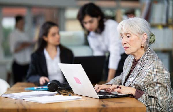 3E4WXGK Elderly woman works on laptop with female colleagues