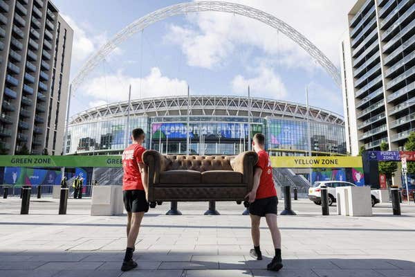 EDITORIAL USE ONLY Bradley Lemaire (left) and Callum Barton (right) deliver a sofa owned by competition winners, Sarah Carter