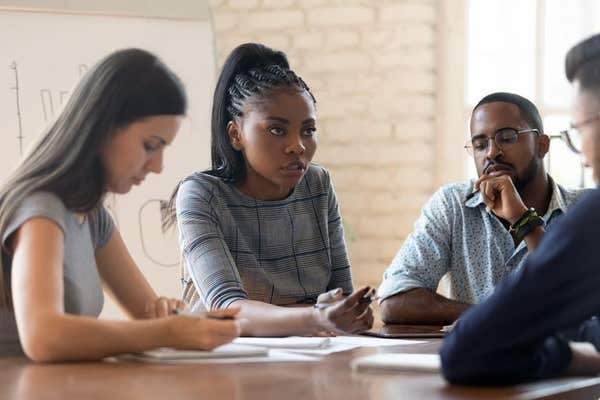 2B1MF0C Serious anxious colleagues gathered together in boardroom solve work problems
