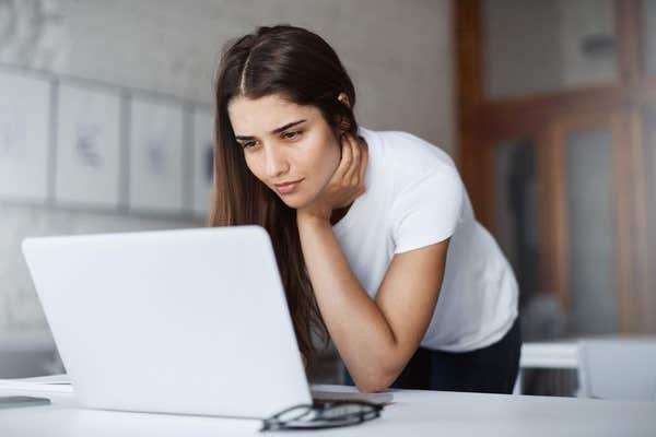 2F565GA Portrait of beautiful woman using a laptop looking at party photos from a bachelor party having a grin.