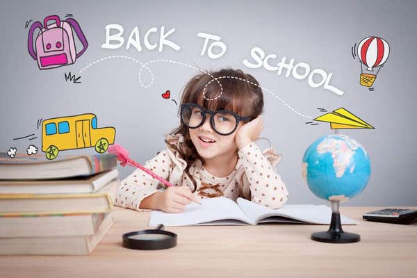 2CFEADH back to school concept. cute little girl wear glasses do homework at home with word back to school and cute cartoon o