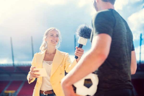 2CT84M0 Reporter interviewing football player in a stadium