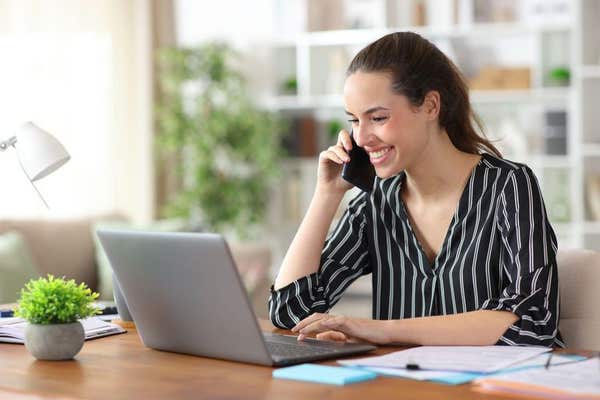 3DTNTDY Happy freelance worker talking on phone using laptop working at home