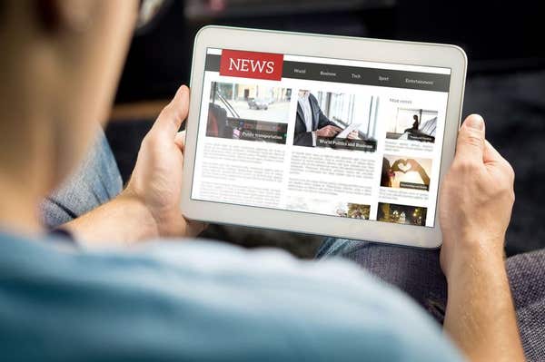 2B8CX60 Online news article on tablet screen. Electronic newspaper or magazine. Latest daily press and media. Mockup of digit