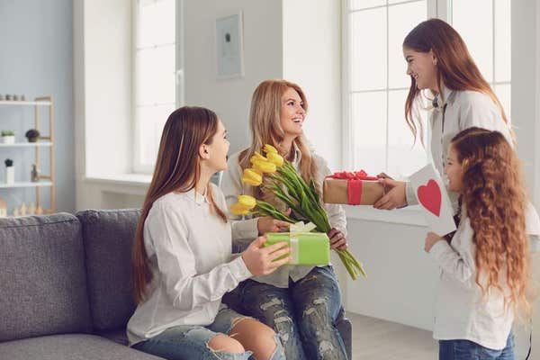 2B2NX00 Happy Mother’s Day. Children daughters give mom a bouquet of flowers at home.