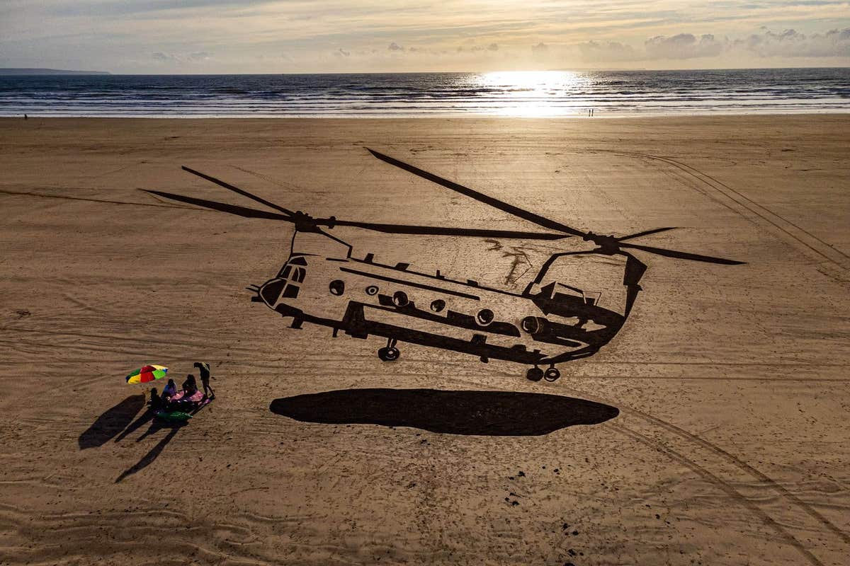 EDITORIAL USE ONLY Aerial views of a 75-metre piece of sand art depicting a military Chinook helicopter on Saunton Sands beac