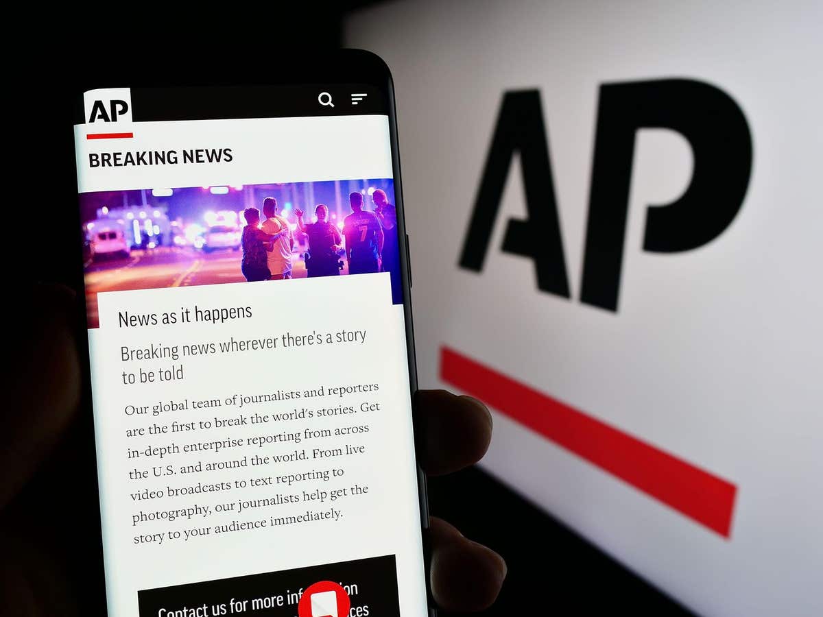 2RD1JCN Person holding smartphone with website of US news agency Associated Press (AP) on screen in front of logo. Focus on c
