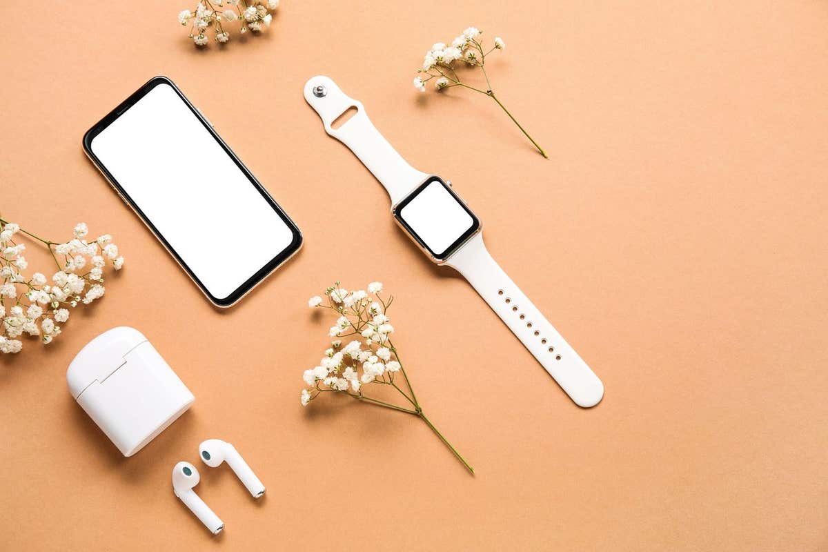 2HJA4B4 Modern mobile phone, earphones, smartwatch and flowers on color background