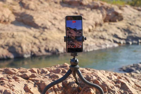 3EB35T7 A closeup of a Phone on tripod recording scenic Rocky River stream outdoor (Travel vlogger soots landscape)