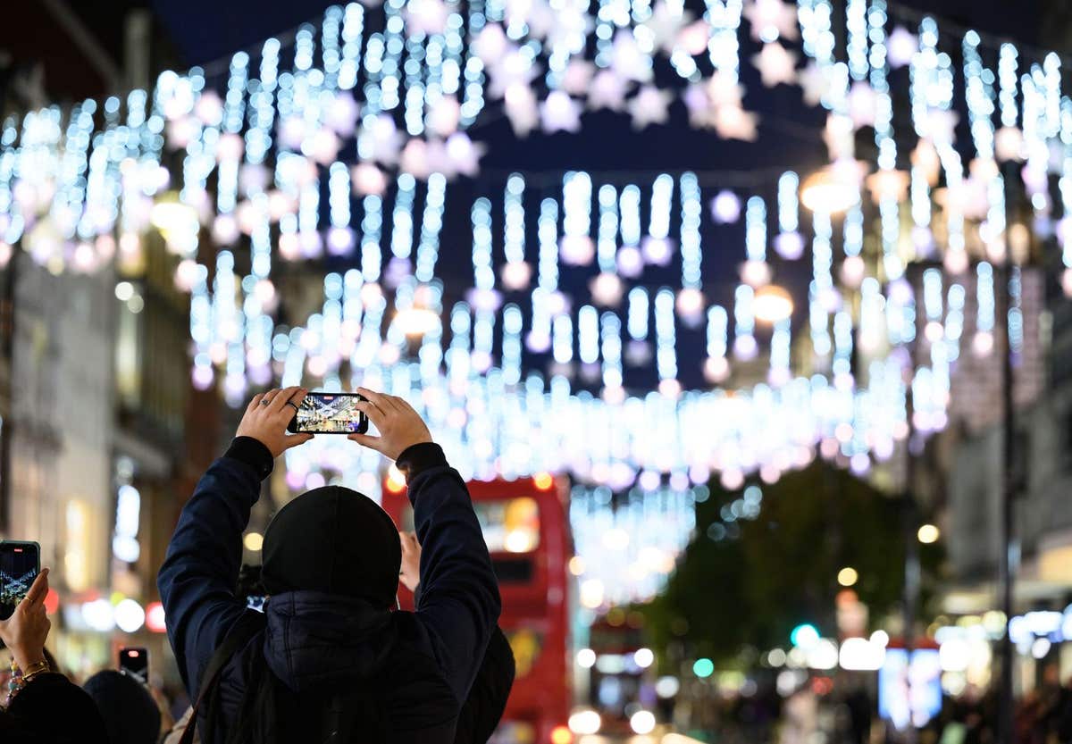 EDITORIAL USE ONLY A person takes a picture of the Oxford Street Christmas lights in London, following the switch-on in partn