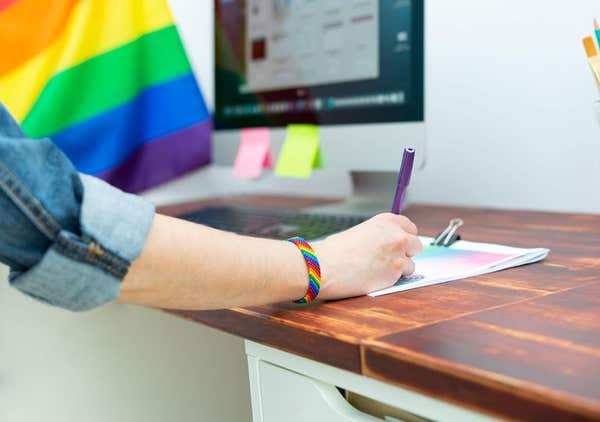 2FK5CMC Woman’s hand working in office with LGBT decor and accessories. Cultura LGBTQIA