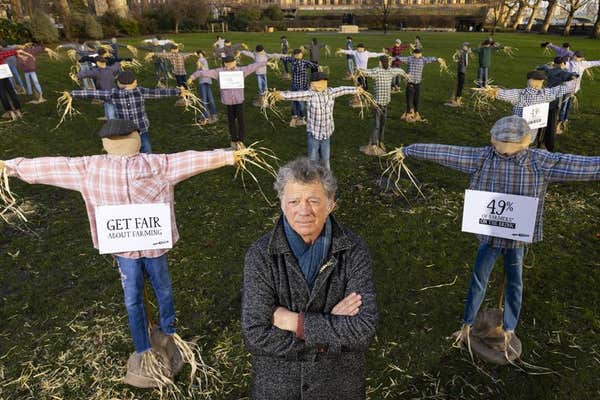 EDITORIAL USE ONLY Riverford founder Guy Singh-Watson in front of 49 scarecrows outside the Houses of Parliament in London, a