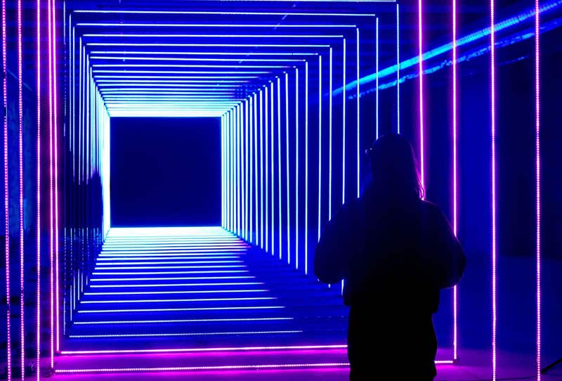 A lady stands in front of On Your Wavelength, an installation presented at the Canary Wharf winter lights festival, as sculptures, structures and installations are presented in different forms of light technology.